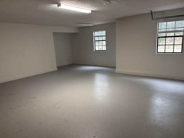spare room featuring concrete floors, baseboards, and a textured ceiling