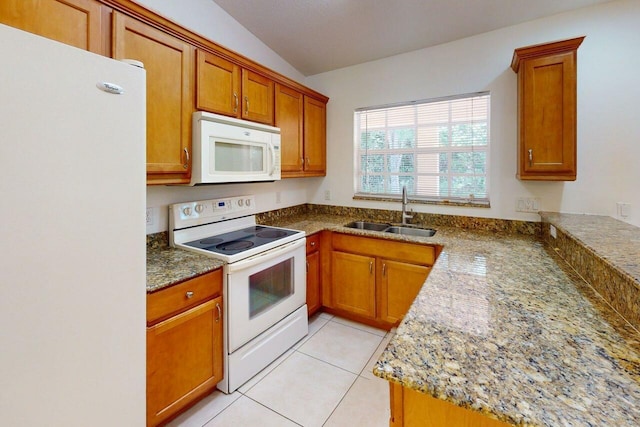 kitchen with a sink, white appliances, light tile patterned floors, and brown cabinets