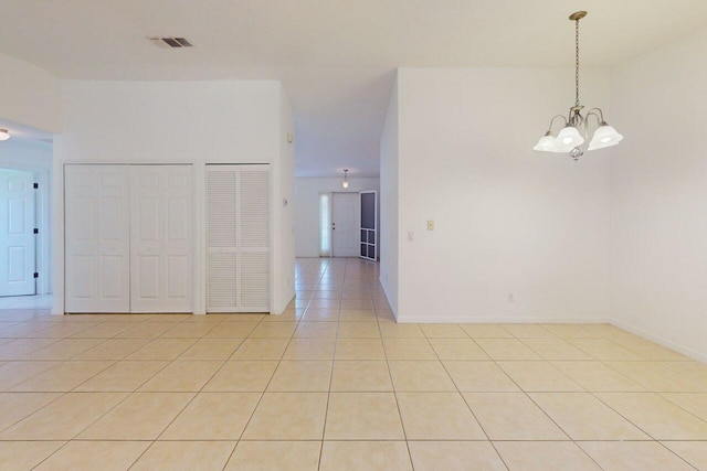 spare room featuring a chandelier, light tile patterned floors, visible vents, and baseboards