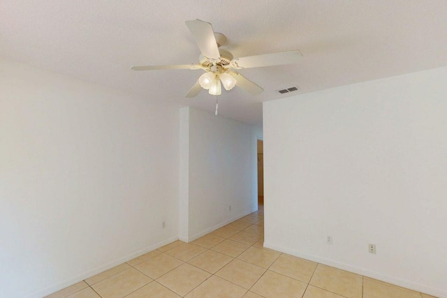 empty room with light tile patterned flooring, baseboards, a ceiling fan, and visible vents