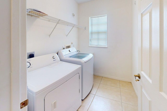 clothes washing area with baseboards, separate washer and dryer, laundry area, and light tile patterned flooring