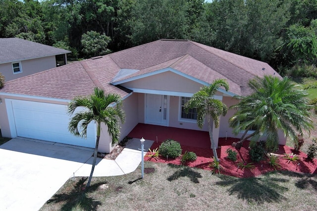 view of front of house with driveway, stucco siding, a shingled roof, and an attached garage