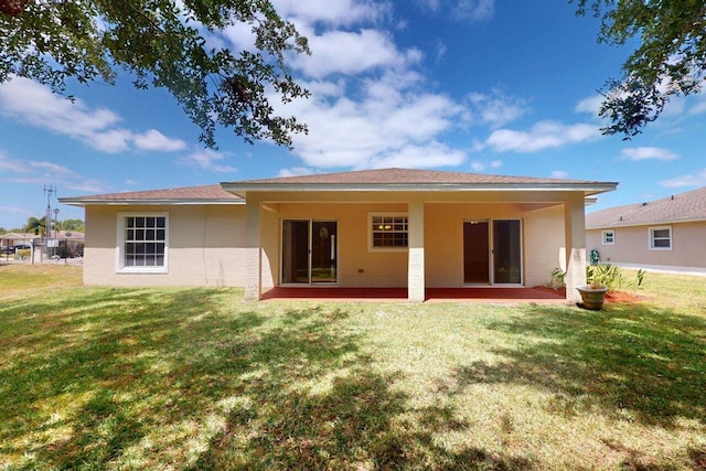 rear view of house featuring a yard, stucco siding, and a patio