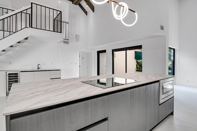 6560 Las Flores Dr, Boca Raton, FL 33433 - kitchen featuring high vaulted ceiling, black electric cooktop, wine cooler, stainless steel microwave, and modern cabinets