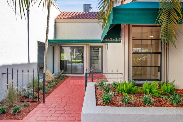 6560 Las Flores Dr, Boca Raton, FL 33433 - view of exterior entry with stucco siding, a tiled roof, and fence