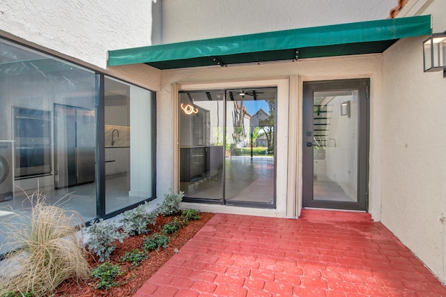 6560 Las Flores Dr, Boca Raton, FL 33433 - doorway to property featuring stucco siding, washer / clothes dryer, and a sink