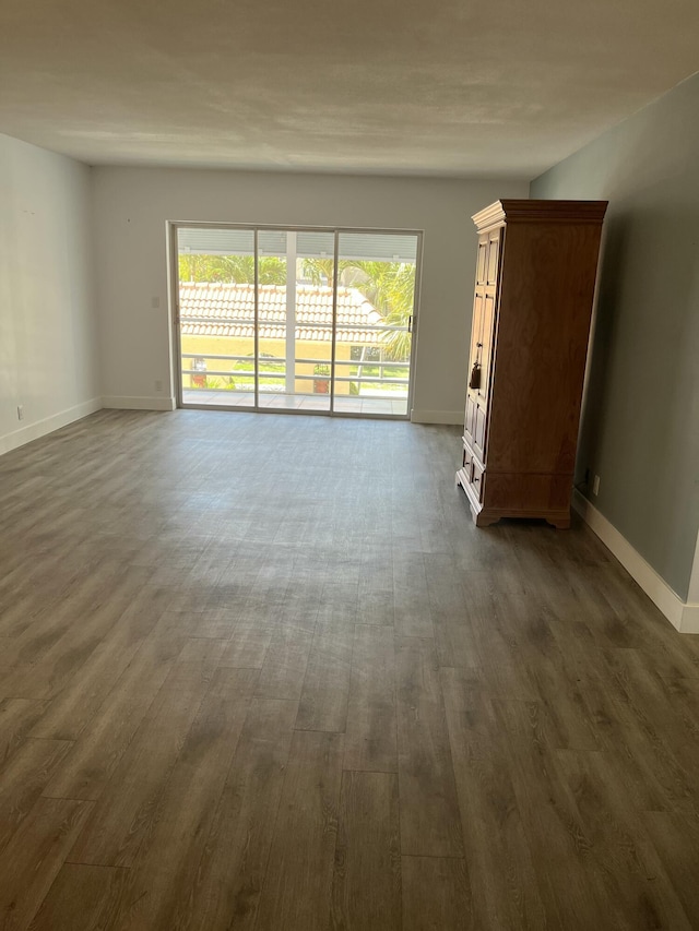 spare room with dark wood-style flooring, baseboards, and plenty of natural light