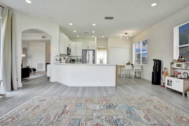 kitchen featuring appliances with stainless steel finishes, visible vents, arched walkways, and light wood-style floors