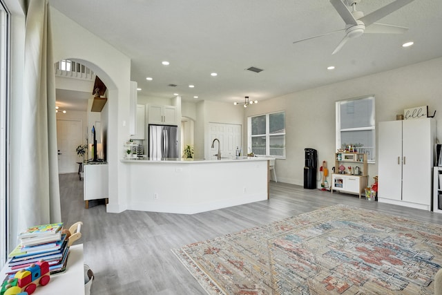 interior space with freestanding refrigerator, light wood finished floors, open floor plan, and a ceiling fan