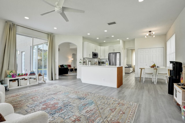 living area with ceiling fan, arched walkways, light wood finished floors, and recessed lighting