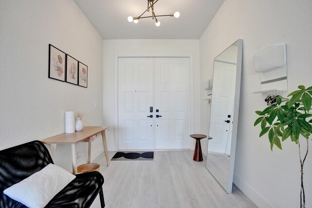 foyer entrance with light wood-style floors, a chandelier, and baseboards