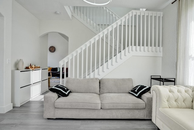 living area featuring stairway, wood finished floors, and arched walkways