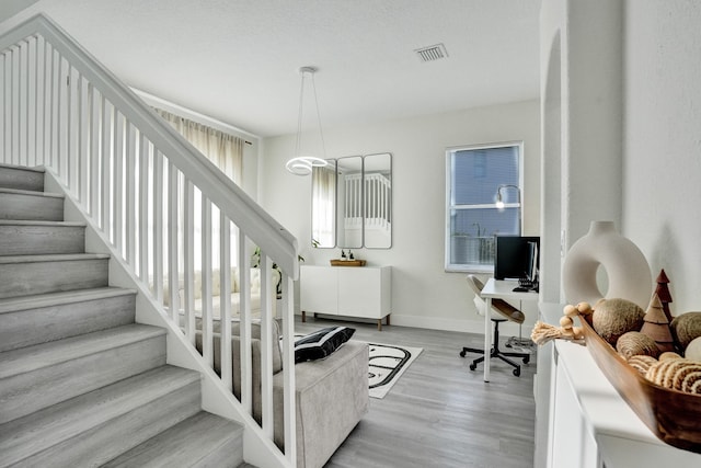 stairway featuring baseboards, visible vents, and wood finished floors