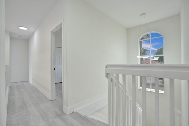 hall with baseboards, an upstairs landing, and wood finished floors