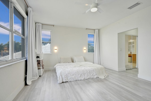 bedroom with multiple windows, baseboards, visible vents, and wood finished floors