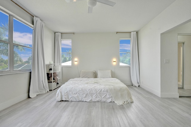 bedroom with baseboards, multiple windows, and wood finished floors
