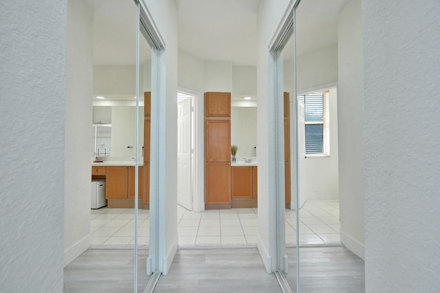 corridor with light wood finished floors and a textured wall