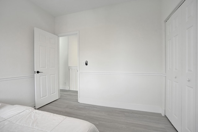 bedroom featuring a closet, light wood-style flooring, and baseboards