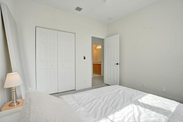 bedroom with baseboards, a closet, visible vents, and wood finished floors