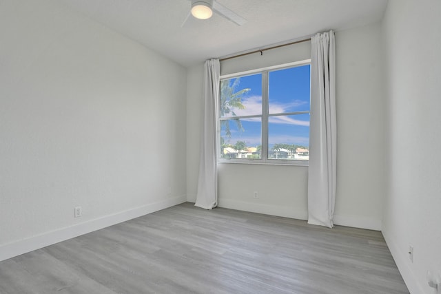 empty room with wood finished floors, baseboards, and a ceiling fan