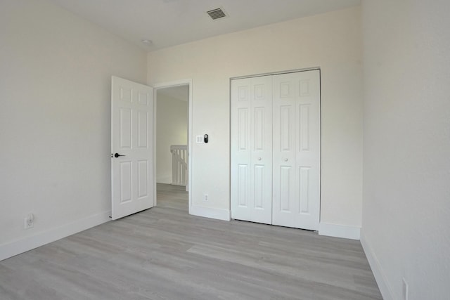 unfurnished bedroom with baseboards, a closet, visible vents, and wood finished floors