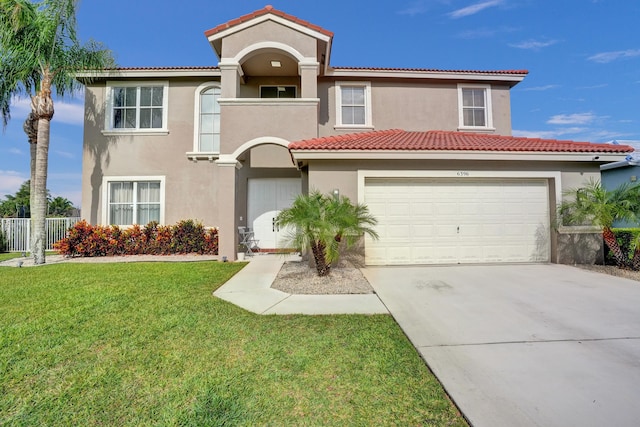 mediterranean / spanish home with driveway, fence, stucco siding, a tile roof, and a front lawn