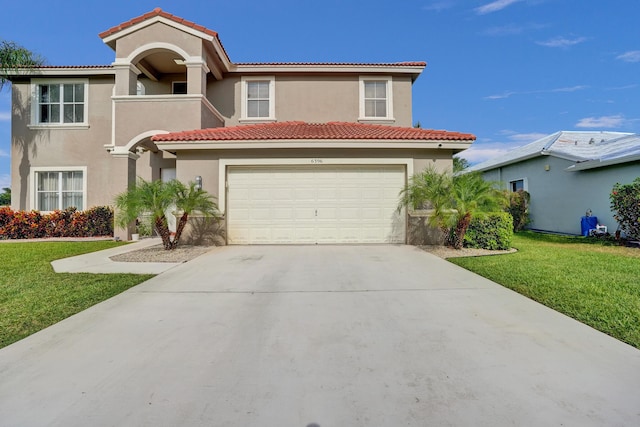 mediterranean / spanish-style house with driveway, a garage, stucco siding, a front yard, and a tiled roof
