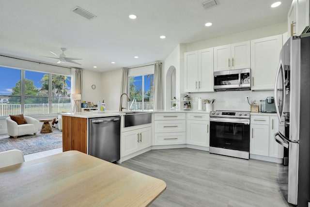 kitchen with a peninsula, stainless steel appliances, visible vents, and open floor plan