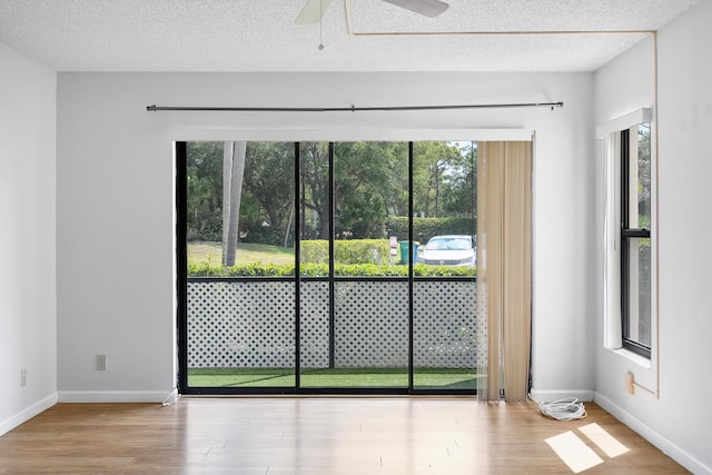 unfurnished room featuring plenty of natural light, wood finished floors, and a textured ceiling
