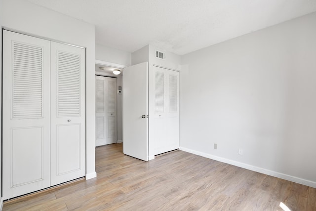 unfurnished bedroom with a textured ceiling, baseboards, visible vents, and light wood-style floors