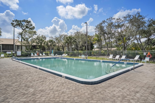 community pool with a patio and fence
