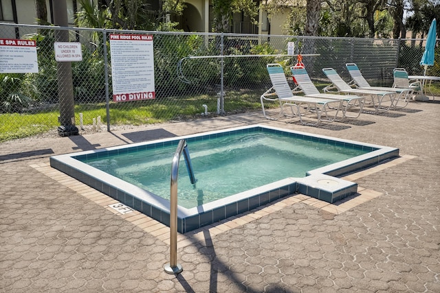 view of pool with fence and a community hot tub