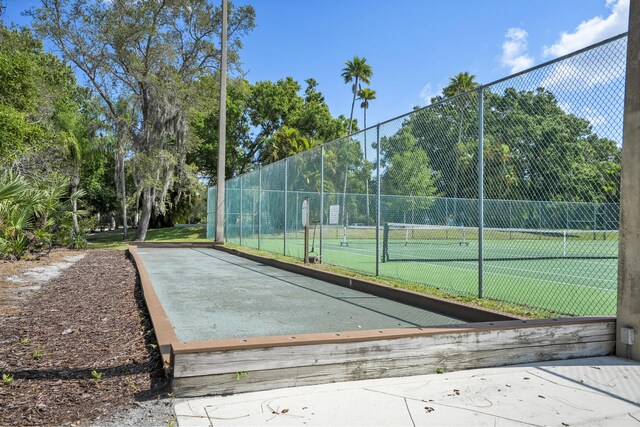 exterior space with fence and a tennis court