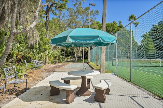 view of community with a tennis court and fence