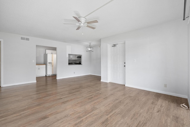 unfurnished living room featuring light wood-type flooring, visible vents, baseboards, and ceiling fan with notable chandelier
