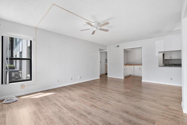 unfurnished living room with light wood finished floors, a textured ceiling, visible vents, baseboards, and ceiling fan