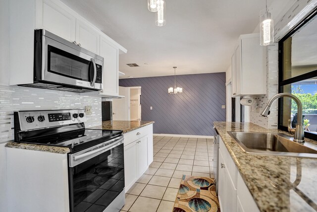 kitchen featuring appliances with stainless steel finishes, a sink, tasteful backsplash, a chandelier, and white cabinets