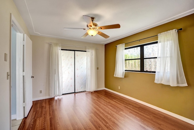 unfurnished bedroom with wood finished floors, baseboards, and a ceiling fan