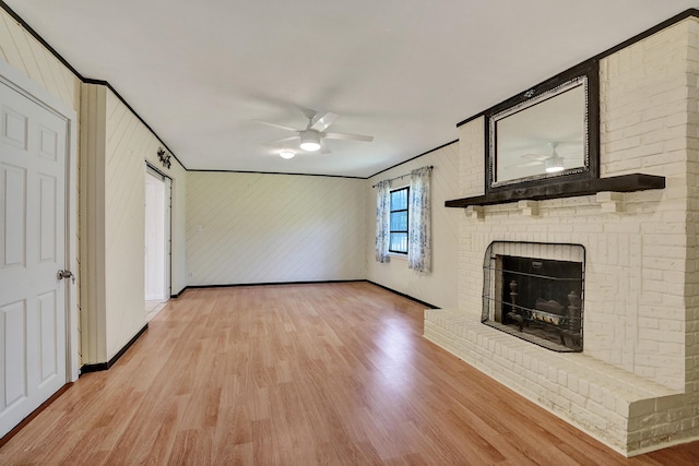 unfurnished living room featuring a ceiling fan, light wood-type flooring, a fireplace, crown molding, and baseboards