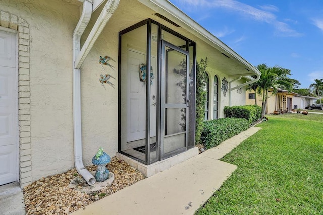 doorway to property with stucco siding and a yard