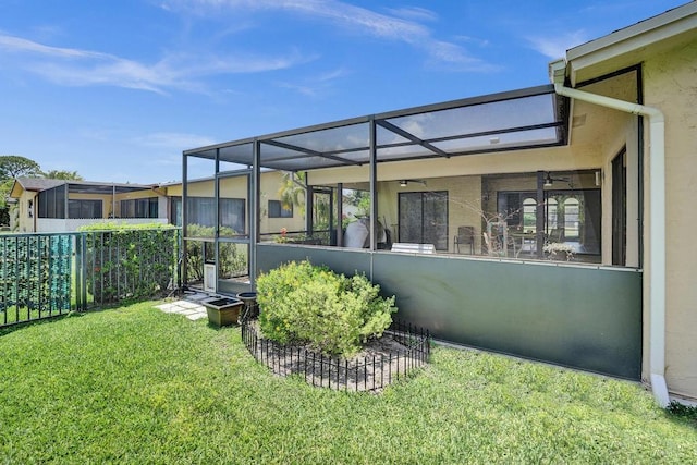 rear view of house featuring a ceiling fan, stucco siding, and glass enclosure