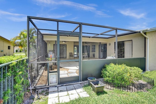 rear view of property with a ceiling fan, stucco siding, a lanai, and a patio area