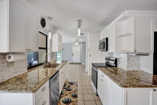 kitchen with appliances with stainless steel finishes, a sink, white cabinetry, ceiling fan, and backsplash