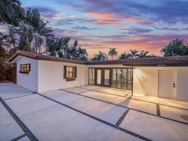 back of property with stucco siding, a tiled roof, and a patio