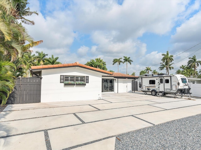 view of front facade featuring concrete driveway, a tiled roof, stucco siding, and fence