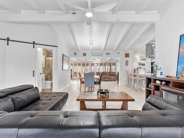living room with ceiling fan, lofted ceiling with beams, light wood-style flooring, and a barn door