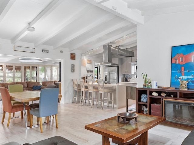 living area featuring rail lighting, lofted ceiling with beams, and light wood-type flooring