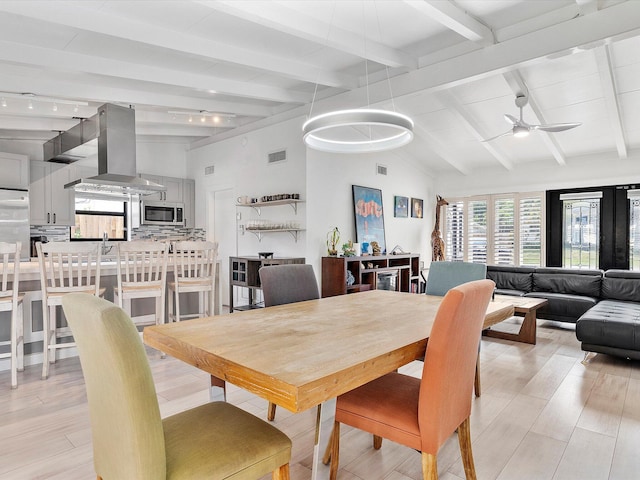 dining area with ceiling fan, lofted ceiling with beams, light wood finished floors, and visible vents