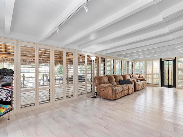 sunroom / solarium featuring beamed ceiling, wood finished floors, and track lighting