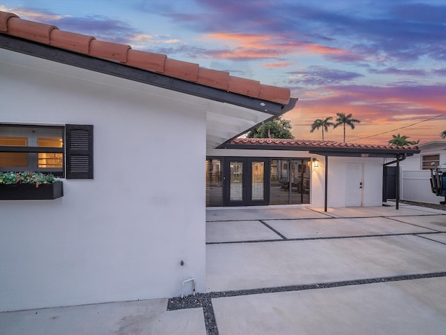 rear view of house featuring stucco siding, a patio area, and a tiled roof